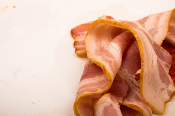 Slices of sausage and bacon on a white background. Close up.