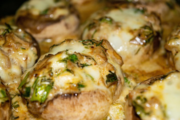 Mushrooms baked in the oven with cheese, green onions and dill. Close up.