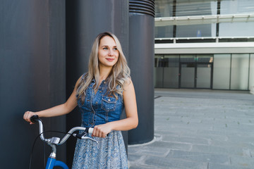 Lifestyle and health in the city. Active fashionable blonde woman with vintage bike on urban background. Good day for a ride, healthy life, street biking concept.