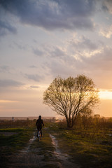 Girl in jacket and cap riding bicycle into susnet