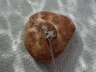 Shiny translucent heart pendant on natural stone in the sunlight