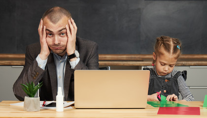 Father Working from home on laptop during quarantine. Little child girl make noise and distracts...