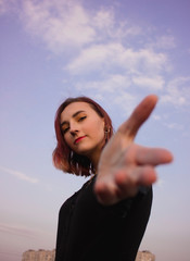 Young girl with outstretched hand on a background of blue sky