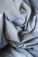 Piece of blue fabric with wrinkles. Natural light and shadows.