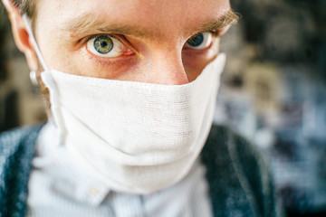 Portrait of a bearded man in a gauze mask and looking at the camera. Preventive protection of your own health from viral infection. Coronavirus concept.