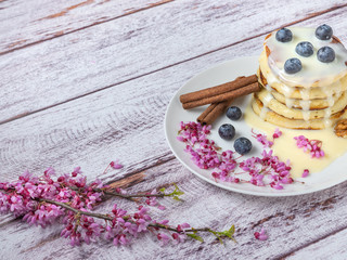 view to pancake in white plate with blossom branches on wooden table with copy space