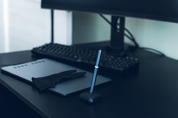 black graphic tablet, monitor and keyboard on a black table and green background, the place of work of a graphic designer at home. Remote work of a modern artist.