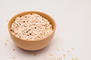 Oat flakes in bowl on white background. Copy space