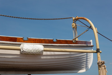 Old wooden lifeboat hoisted up on the side of an old tall ship, rigging details, horizontal aspect