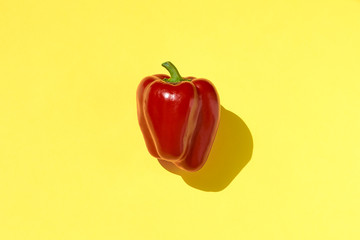 Fresh red bell pepper on a yellow background.