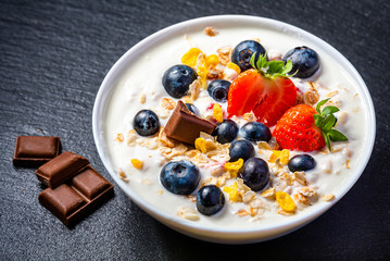 Yogurt with granola, strawberries, blueberries and chocolate.