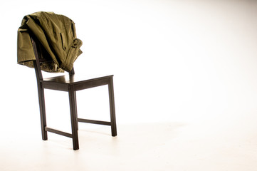 Jacket draped over wooden chair on white background
