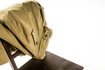 Jacket draped over wooden chair on white background