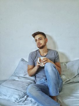 un bel ragazzo che beve caffe' a letto appena sveglio