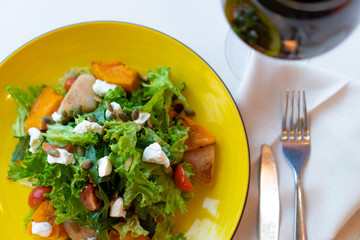salad with baked vegetables, herbs, nuts and kerm cheese and glass of wine. Top view