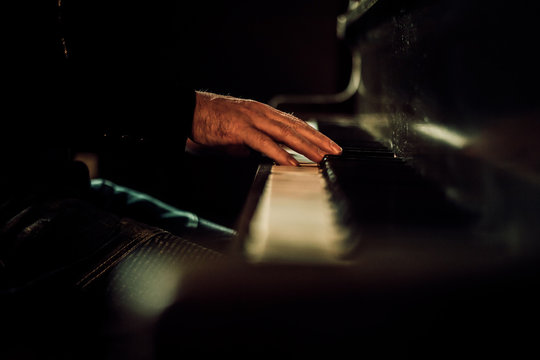 Hands Playing Piano Keys In Dark Space