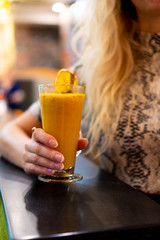 a girl drinks an orange drink from a glass
