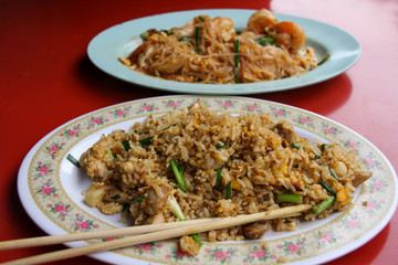 Vegetable rice dish with flower decorated plate and defocused noodles background