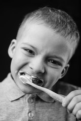 the child is brushing his teeth. black and white portrait of a preschooler