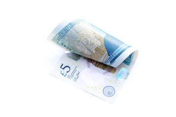 Close-up of a rolled five pound stirling English paper money isolated on white background