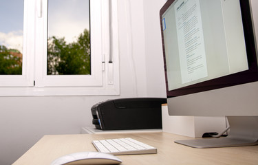 Fototapeta premium Photograph of a computer in an office and a window overlooking the street to represent the idea of teleworking during the confinement caused by Covid-19