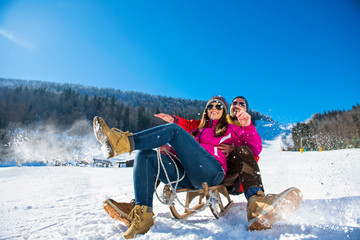 Young happy couple sledding in winter at ski center