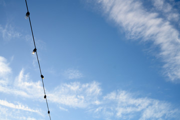 Blue sky with white clouds and twinkle lights, room for text