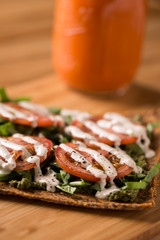 Raw Pizza with gluten free crust, tomatoes, cashew cheese with juice in the background