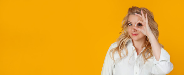 Blond woman feeling optimistic happy showing ok circle over eye smiling happily. feels happy...