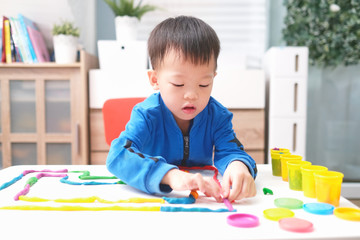 Little Asian boy child having fun playing colorful modeling clay / Play dough at home, Educational toys for kid, Montessori education, Child at home, kindergarten closed during Covid-19 health crisis