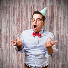 Man wearing a red bow tie and party hat. Looking funny.