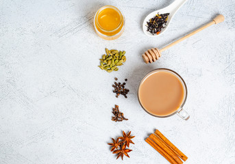 A traditional Indian drink masala tea in a glass cup with ingredients for cooking