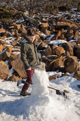 Young boy building a small snowman