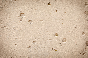 Texture of a concrete beige, wall with bumps, cracks, splashes, painted beige. Abstract background.