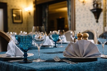 Photo of a professional restaurant service. Table served with a glass of blue glass, forks and knives