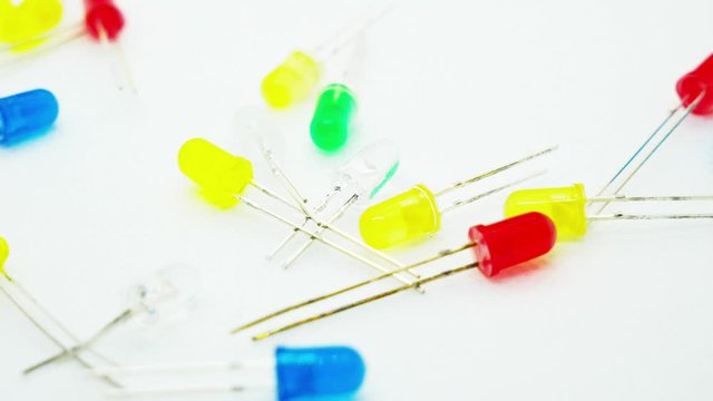 Fallende Leuchtdioden (LED) in verschiedenen Farben auf wei&szlig;em Untergrund