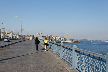 Young couple walking through empty Galata Bridge during Coronavirus restrictions.