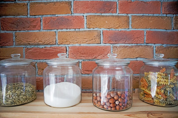 Walnuts, pasta,grains and salt in glas jars in modern loft design kitchen in front of bricked wall, cooking concept