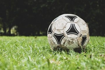 Fototapeta na wymiar Old soccer ball on wet grass