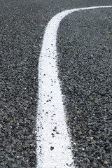 Fototapeta premium Close-up White Curving Vertical Road Marking On Gray Gravel Road