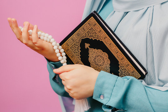 Muslim girl holding quran and islamic rosary in her hands