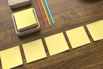 Yellow sticky notes and colored pencils on a wooden surface