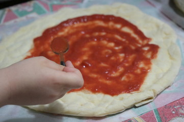 preparazione di una pizza fatta in casa con pomodoro, mozzarella, olive, capperi e olio extra vergine d'oliva - 342568113