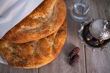 Ramadan concept, close-up of pita bread , Dried dates, dried date fruit and a glass of water for iftar on topview of decorative table