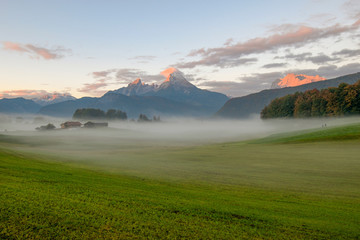 Famous Mt. Watzmann near Berchtesgaden with farmhouse and mist at sunrise