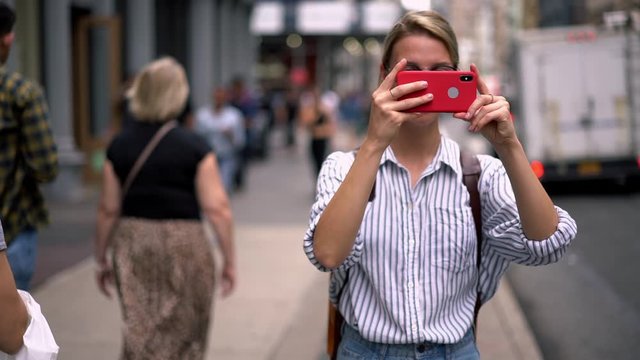 Millennial hipster girl tourist in casual outfit photographing buildings architecture and in New York using camera and application on modern cellular phone, slow motion effect. Female wanderlust 
