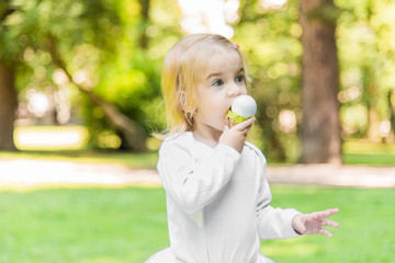 A little beautiful girl walks in the park with a picnic basket and straw hat. Funny emotional baby.