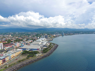 Fototapeta premium Manado Indonesia June 28, 2020 : Aerial skyscrapers marina in the sunny day with front line of office, home, urban city Manado Indonesia