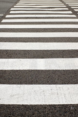 A closeup shot of a zebra crosswalk in an urban center.