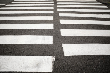 A closeup shot of a zebra crosswalk in an urban center.